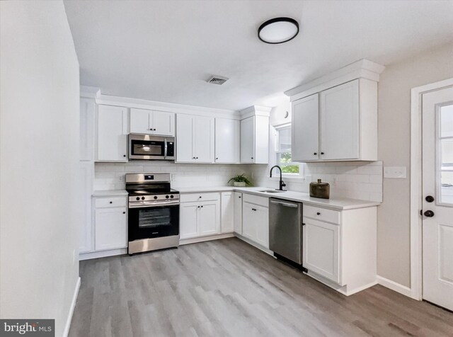 6985 Old Harrisburg Rd, York Springs, PA 17372 - kitchen featuring appliances with stainless steel finishes, a sink, light wood finished floors, decorative backsplash, and baseboards