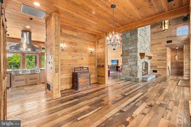 2042 Folk Rd, Fogelsville, PA 18051 - unfurnished living room featuring wooden ceiling, wooden walls, hardwood / wood-style flooring, a stone fireplace, and a chandelier