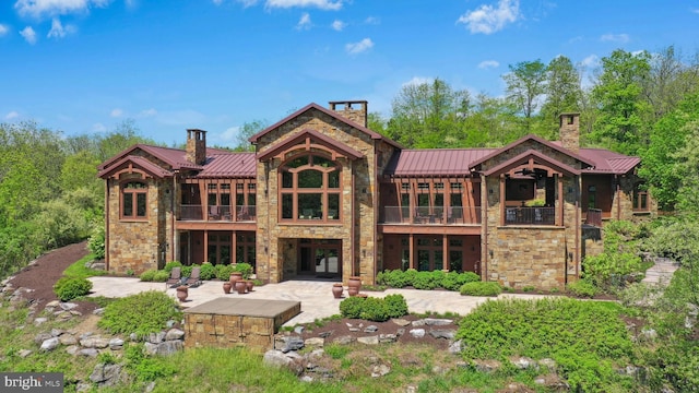2042 Folk Rd, Fogelsville, PA 18051 - rear view of house with a chimney, a standing seam roof, a balcony, and stone siding