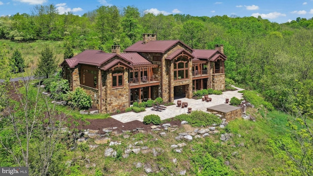 2042 Folk Rd, Fogelsville, PA 18051 - back of house with a chimney, stone siding, a patio, a forest view, and a balcony