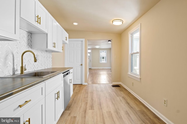 303 Coral St, Lancaster, PA 17603 - kitchen with dishwasher, a sink, light wood finished floors, decorative backsplash, and white cabinetry