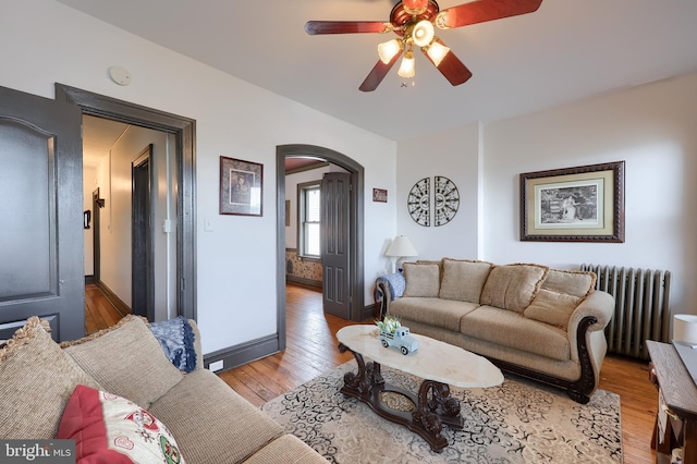 342 N Newberry St, York, PA 17401 - living area featuring radiator, arched walkways, light wood-style flooring, a ceiling fan, and baseboards