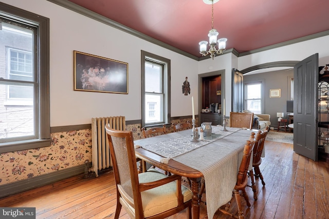 342 N Newberry St, York, PA 17401 - dining space with radiator heating unit, arched walkways, wood-type flooring, a chandelier, and crown molding