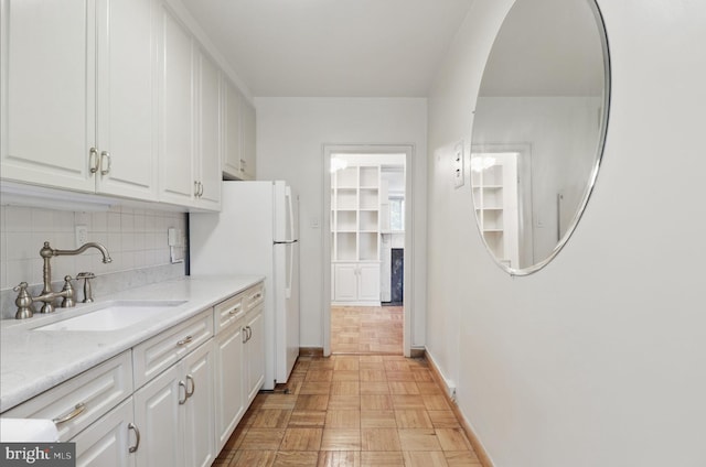 4200 Cathedral Ave NW Unit 317, Washington, DC 20016 - kitchen with a sink, baseboards, white cabinetry, and tasteful backsplash