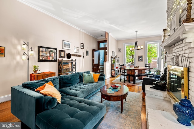 522 S Hanover St, Baltimore, MD 21201 - living area with light wood finished floors, crown molding, baseboards, a chandelier, and a brick fireplace