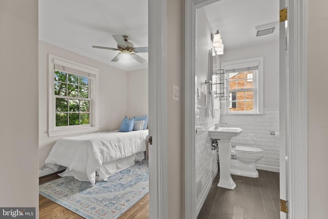 823 Church St, Alexandria, VA 22314 - bedroom featuring multiple windows, wood finished floors, ensuite bath, tile walls, and a wainscoted wall