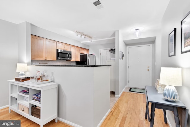 2050 N Calvert St Unit 106, Arlington, VA 22201 - kitchen featuring stainless steel microwave, freestanding refrigerator, light wood-type flooring, dark countertops, and a peninsula