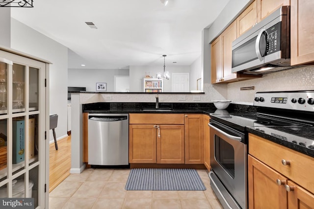 2050 N Calvert St Unit 106, Arlington, VA 22201 - kitchen featuring stainless steel appliances, a chandelier, a peninsula, dark stone countertops, and light tile patterned floors