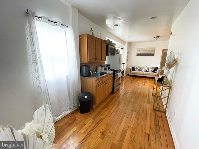 3647 N 19th St, Philadelphia, PA 19140 - kitchen featuring stainless steel appliances, brown cabinetry, light wood-style floors, and open floor plan
