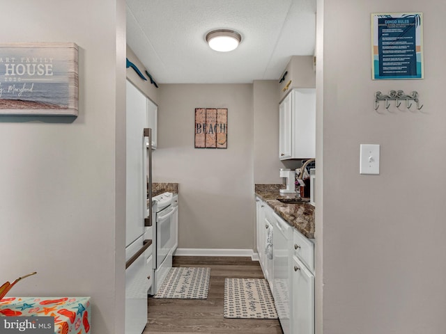4711 Coastal Hwy Unit 538, Ocean City, MD 21842 - kitchen featuring white cabinets, dark wood-type flooring, a sink, dark stone countertops, and baseboards