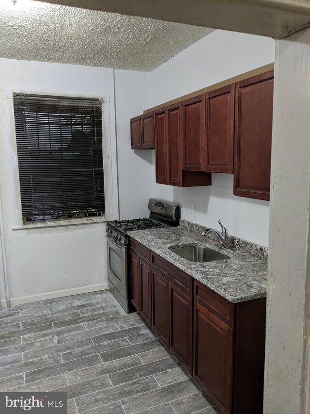4303 N Franklin St, Philadelphia, PA 19140 - kitchen with gas stove, a sink, a textured ceiling, wood finished floors, and light stone countertops