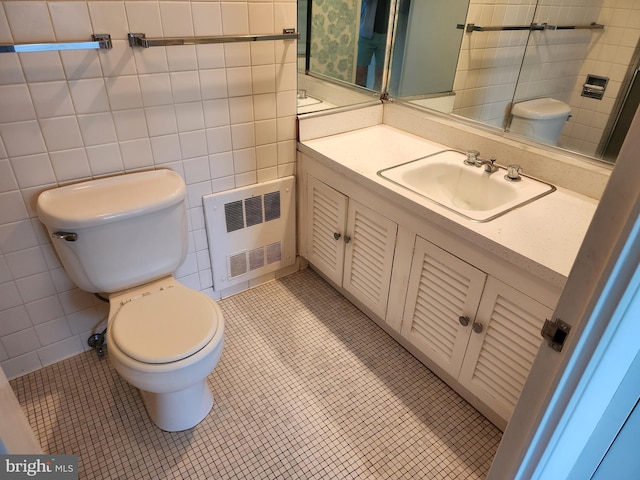 7121 Park Heights Ave Unit 206, Baltimore, MD 21215 - bathroom featuring radiator, toilet, vanity, tile walls, and tile patterned flooring