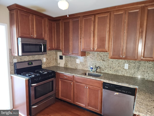 7121 Park Heights Ave Unit 206, Baltimore, MD 21215 - kitchen featuring appliances with stainless steel finishes, a sink, decorative backsplash, brown cabinets, and light stone counters