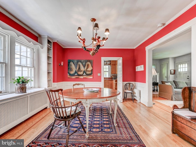 326 Saint Dunstans Rd, Baltimore, MD 21212 - dining area with wood finished floors, a chandelier, radiator, a wainscoted wall, and crown molding