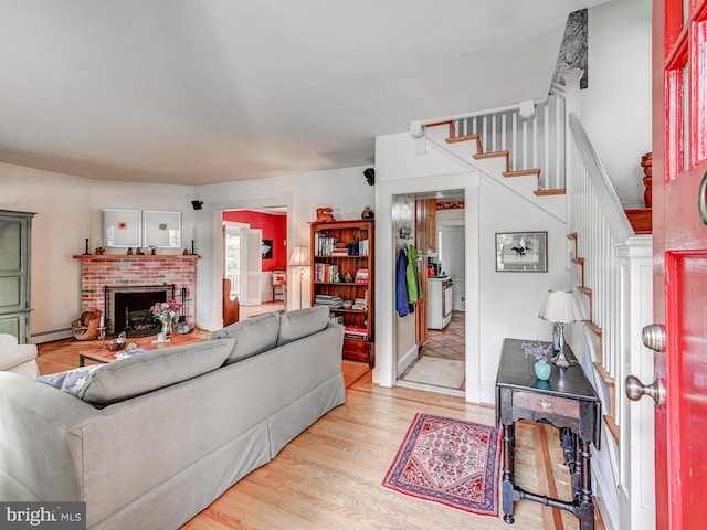 326 Saint Dunstans Rd, Baltimore, MD 21212 - living area with stairs, a fireplace, light wood-style flooring, and a baseboard heating unit