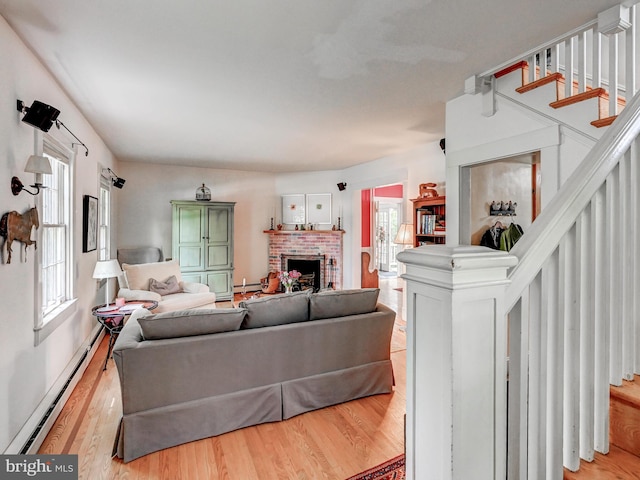 326 Saint Dunstans Rd, Baltimore, MD 21212 - living area with a baseboard heating unit, light wood-style flooring, a brick fireplace, stairs, and baseboard heating