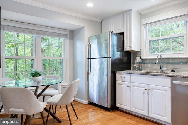 6600 Rockleigh Way, Alexandria, VA 22315 - kitchen with stainless steel appliances, a sink, light wood-style flooring, decorative backsplash, and white cabinetry