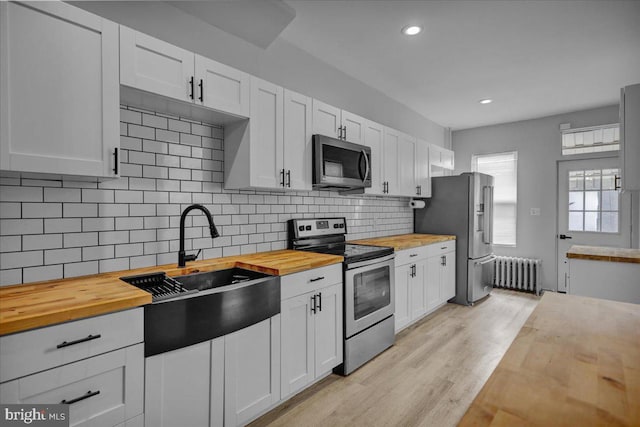 918 Spring St, Reading, PA 19604 - kitchen with wood counters, appliances with stainless steel finishes, radiator heating unit, a sink, and light wood-style floors