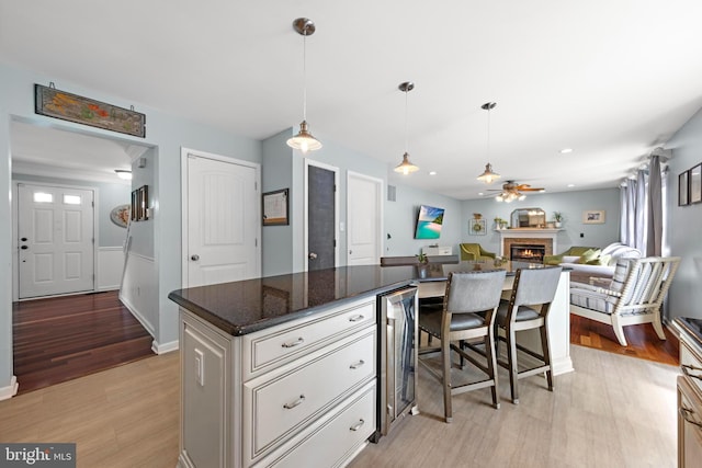 202 Prancer Rd, Egg Harbor Township, NJ 08234 - kitchen with wine cooler, a lit fireplace, light wood-style floors, a center island, and ceiling fan