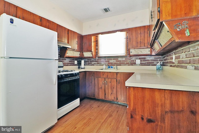 827 Rogers St, Lanoka Harbor, NJ 08734 - kitchen featuring freestanding refrigerator, gas range oven, under cabinet range hood, light countertops, and brown cabinetry