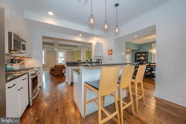 206 Price Ave Unit 2, Narberth, PA 19072 - kitchen with appliances with stainless steel finishes, a peninsula, dark wood-style flooring, a kitchen bar, and recessed lighting