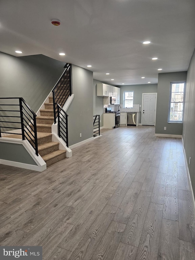 6022 N Lambert St, Philadelphia, PA 19138 - unfurnished living room featuring light wood-type flooring, baseboards, recessed lighting, stairway, and a sink