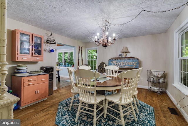 7001 Locust Ct, Owings, MD 20736 - dining space featuring a textured ceiling, a chandelier, wood finished floors, and healthy amount of natural light