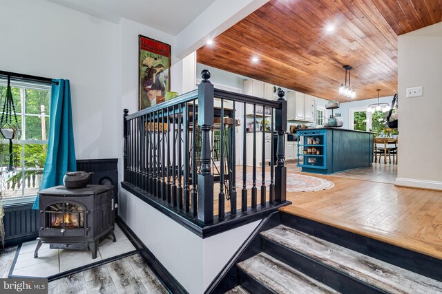 7001 Locust Ct, Owings, MD 20736 - staircase with wood-type flooring, a chandelier, a wood stove, wooden ceiling, and plenty of natural light