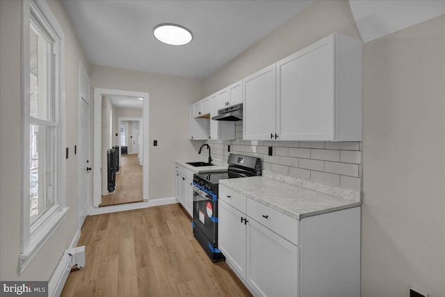1120 N 10th St, Reading, PA 19604 - kitchen featuring range with electric stovetop, under cabinet range hood, a sink, light countertops, and white cabinetry