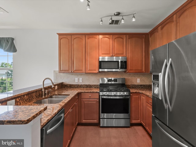 9204 Charleston Dr Unit 407, Manassas, VA 20110 - kitchen with stainless steel appliances, a sink, dark stone countertops, a peninsula, and light wood-style floors