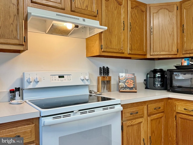 8565 E St, Chesapeake Beach, MD 20732 - kitchen with white range with electric cooktop, under cabinet range hood, light countertops, and brown cabinets