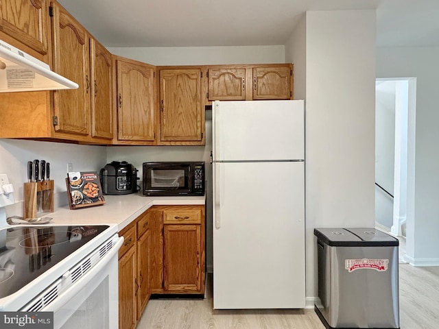 8565 E St, Chesapeake Beach, MD 20732 - kitchen featuring white appliances, light wood-style floors, under cabinet range hood, light countertops, and brown cabinetry
