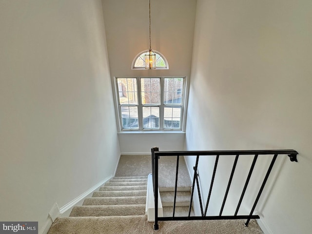 8565 E St, Chesapeake Beach, MD 20732 - staircase featuring carpet, a chandelier, baseboards, and a towering ceiling
