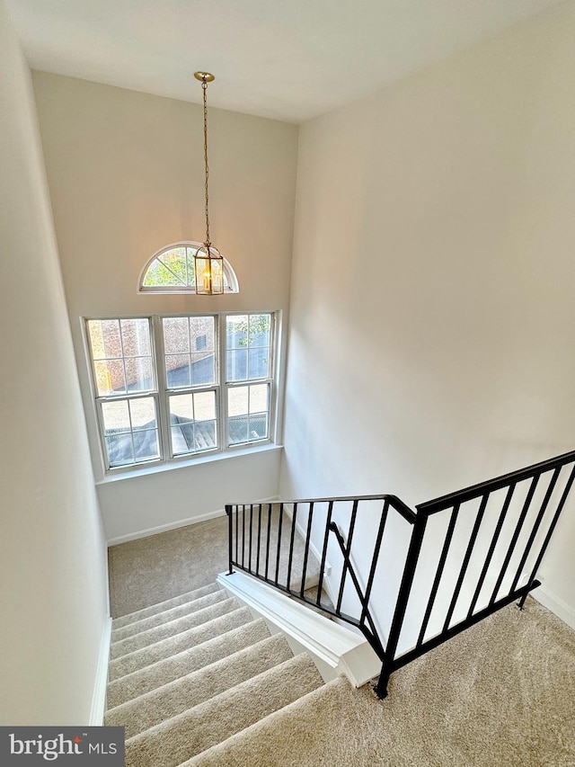 8565 E St, Chesapeake Beach, MD 20732 - stairway with carpet floors, a chandelier, baseboards, and a high ceiling
