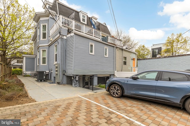 909 Webster St NW Unit 1, Washington, DC 20011 - view of property exterior with central AC unit, a balcony, mansard roof, and uncovered parking