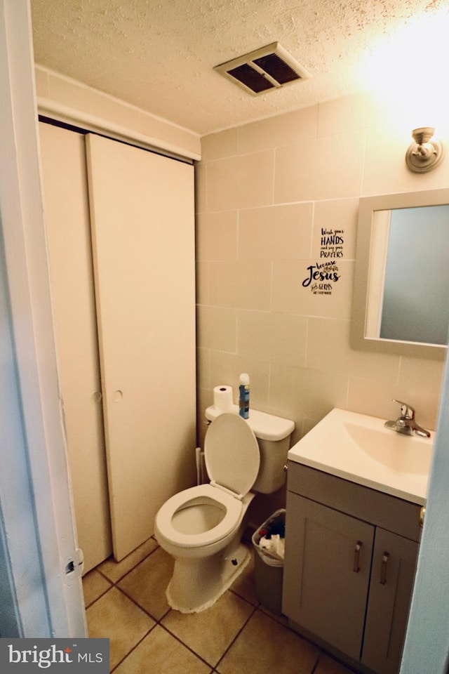 2460 Kilpatrick Pl, Dumfries, VA 22026 - half bath featuring vanity, toilet, a textured ceiling, and tile patterned flooring