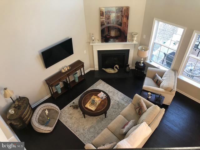 734 Sun Valley Ct, Chester Springs, PA 19425 - living room featuring a fireplace with raised hearth, baseboards, wood finished floors, and a towering ceiling