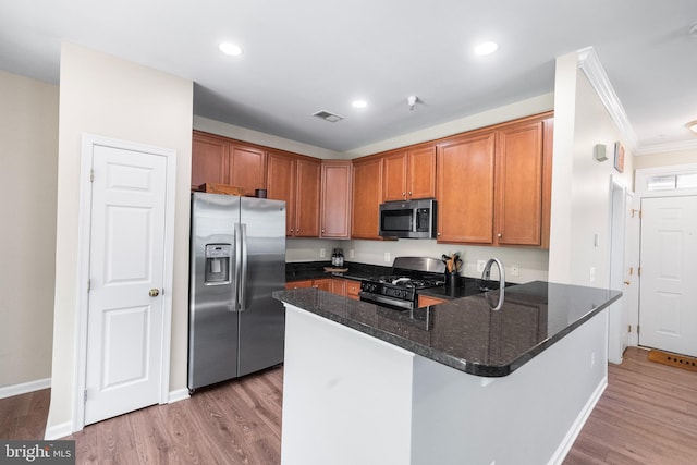 43825 Hickory Corner Ter Unit 104, Ashburn, VA 20147 - kitchen featuring appliances with stainless steel finishes, a peninsula, ornamental molding, dark stone countertops, and light wood-type flooring