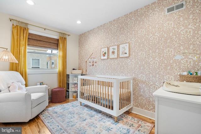 2409 S Watts St, Philadelphia, PA 19148 - bedroom featuring wood finished floors, a nursery area, wallpapered walls, recessed lighting, and baseboards