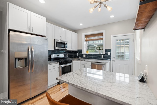 2409 S Watts St, Philadelphia, PA 19148 - kitchen with appliances with stainless steel finishes, a chandelier, white cabinetry, light stone countertops, and recessed lighting