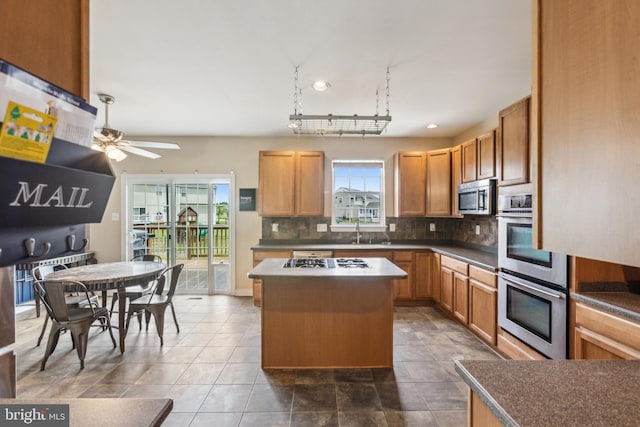 39 Grain Ct, Magnolia, DE 19962 - kitchen featuring appliances with stainless steel finishes, a sink, backsplash, a kitchen island, and a ceiling fan