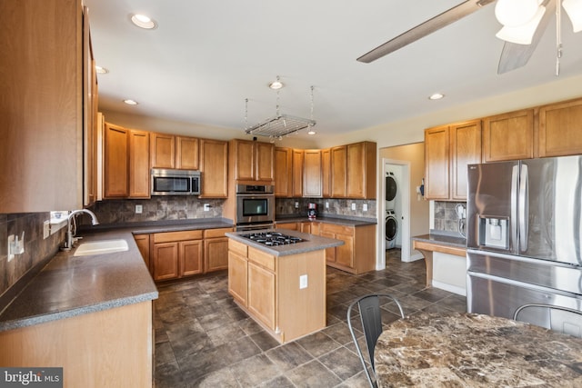 39 Grain Ct, Magnolia, DE 19962 - kitchen with stainless steel appliances, a sink, estacked washer and dryer, decorative backsplash, and a center island