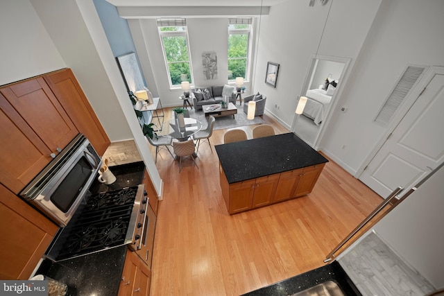2425 L St NW Unit 328, Washington, DC 20037 - kitchen with light wood-type flooring, stainless steel microwave, brown cabinetry, and dark stone countertops
