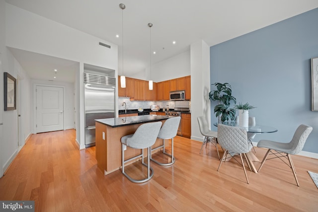 2425 L St NW Unit 328, Washington, DC 20037 - kitchen featuring appliances with stainless steel finishes, dark countertops, a center island, backsplash, and light wood-style flooring