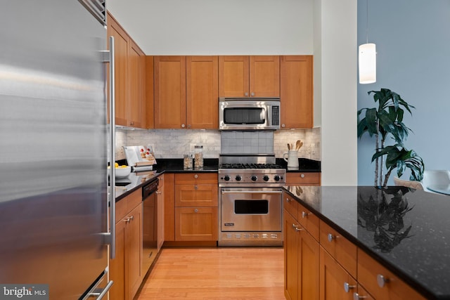 2425 L St NW Unit 328, Washington, DC 20037 - kitchen with appliances with stainless steel finishes, brown cabinets, decorative backsplash, and light wood finished floors