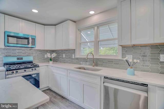 611 Parkview Blvd, Lansdowne, PA 19050 - kitchen with stainless steel appliances, a sink, white cabinets, decorative backsplash, and light stone counters