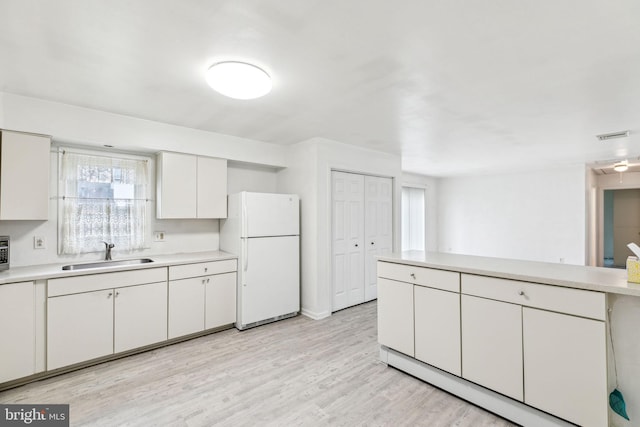 3 Karok Ln, Browns Mills, NJ 08015 - kitchen with freestanding refrigerator, a sink, light countertops, white cabinets, and light wood-style flooring