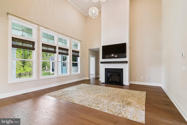 24153 Heartleaf Rd, Frankford, DE 19945 - unfurnished living room with a fireplace, crown molding, dark wood finished floors, baseboards, and a towering ceiling