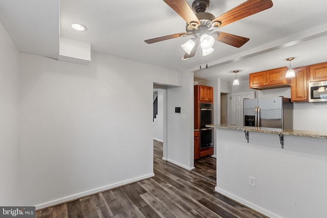 2802 Bruce Pl SE, Washington, DC 20020 - kitchen featuring stainless steel appliances, baseboards, light stone countertops, ceiling fan, and dark wood-type flooring
