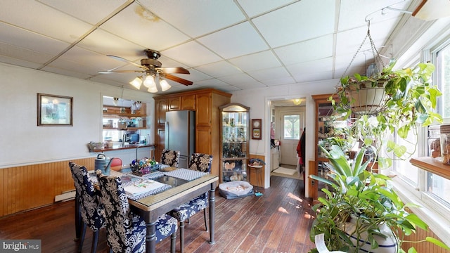5403 Willow Grove Rd, Camden Wyoming, DE 19934 - dining area featuring baseboard heating, dark wood-style floors, ceiling fan, a drop ceiling, and wainscoting